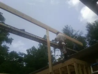 Carpenter setting a ridge beam over a new addition frame — Ice Dam Removal by Roofing Brothers in Opelika