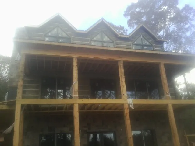 Dormers and porch framing on a large log home under construction — Roof Coating work by our crew in Opelika