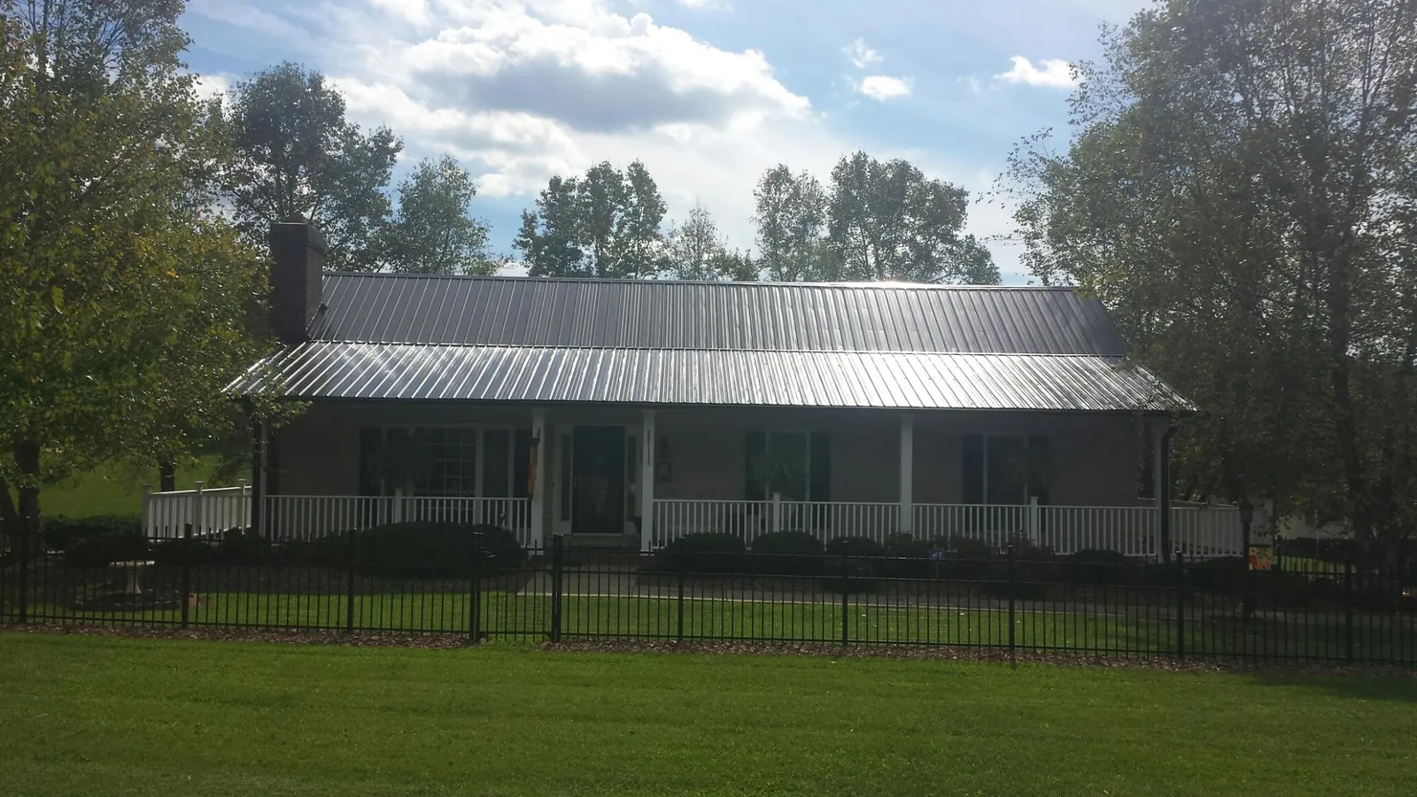 Gray metal roof on a brick ranch with a full width front porch — Gutter Guard Installation work by our crew in Opelika
