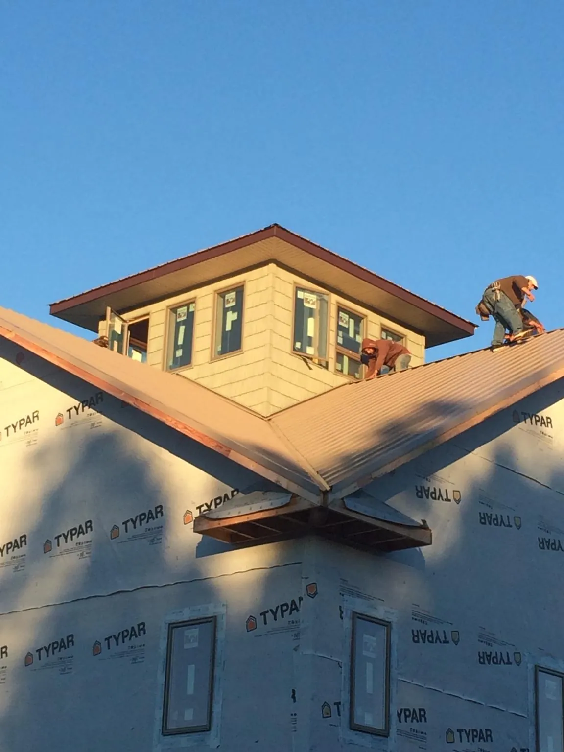 Roofers working around a rooftop cupola on a new metal roof at sunset — Roof Waterproofing in Opelika by Roofing Brothers